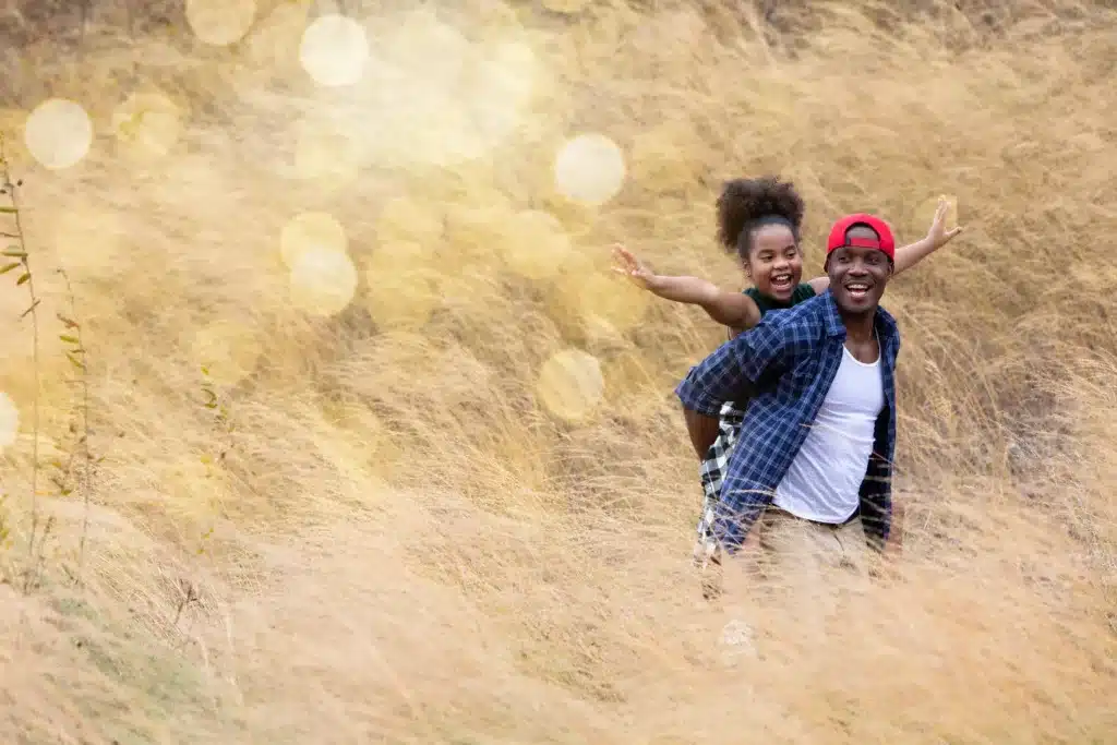 A joyful father and daughter enjoying a piggyback ride in a field, symbolizing the happiness of learning how to ensure business financial health.