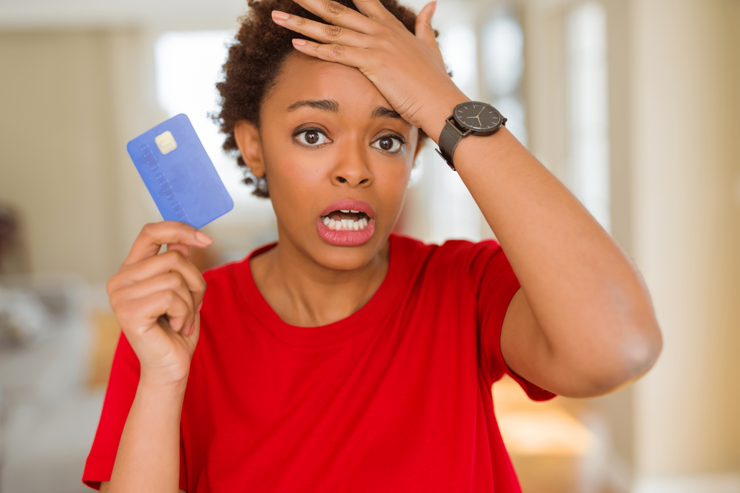 Young african american woman holding credit card stressed with hand on head, shocked with shame and surprise face, angry and frustrated. Fear and upset for mistake
