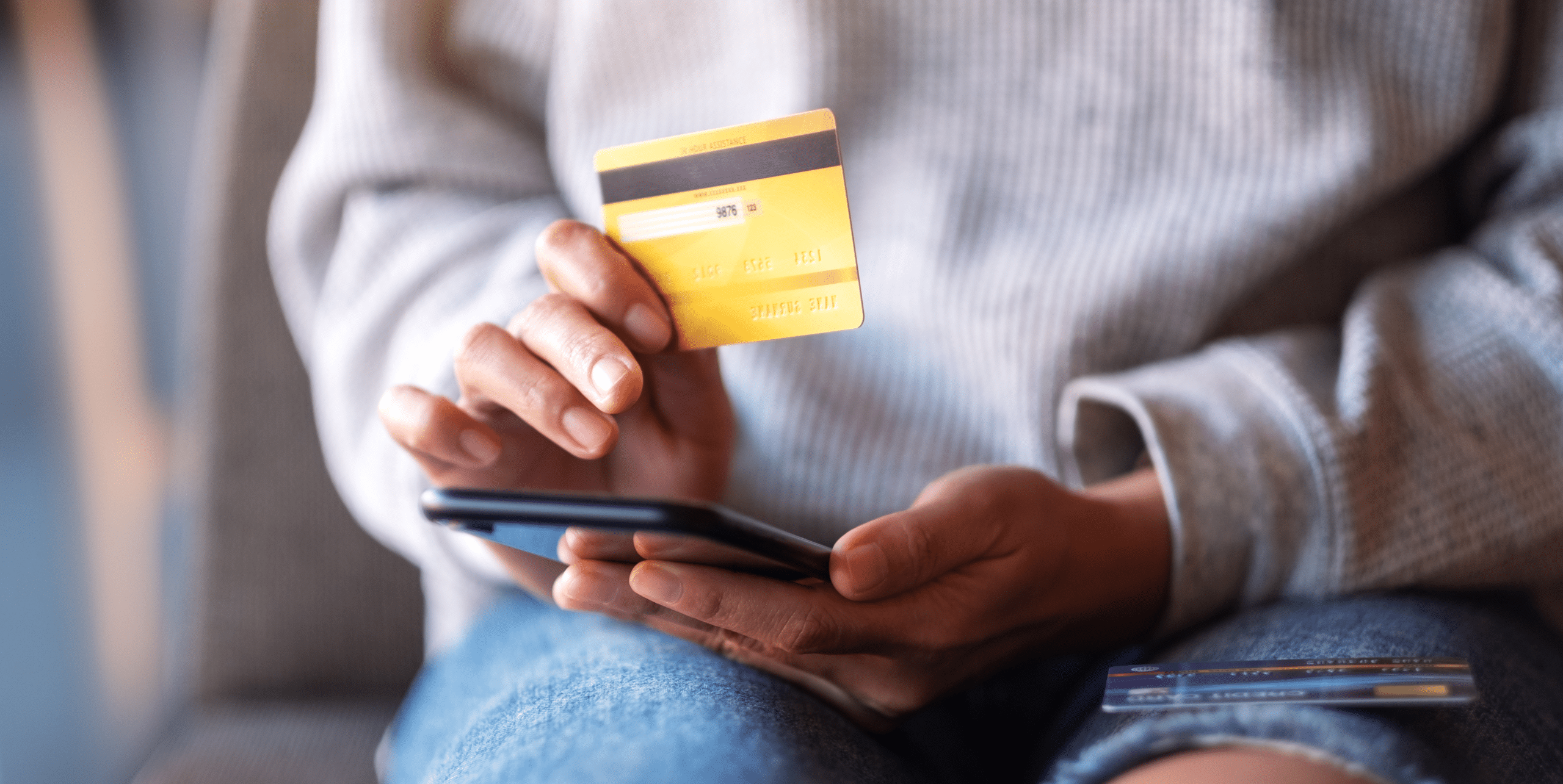 Closeup image of a woman using credit card for purchasing and shopping online on mobile phone