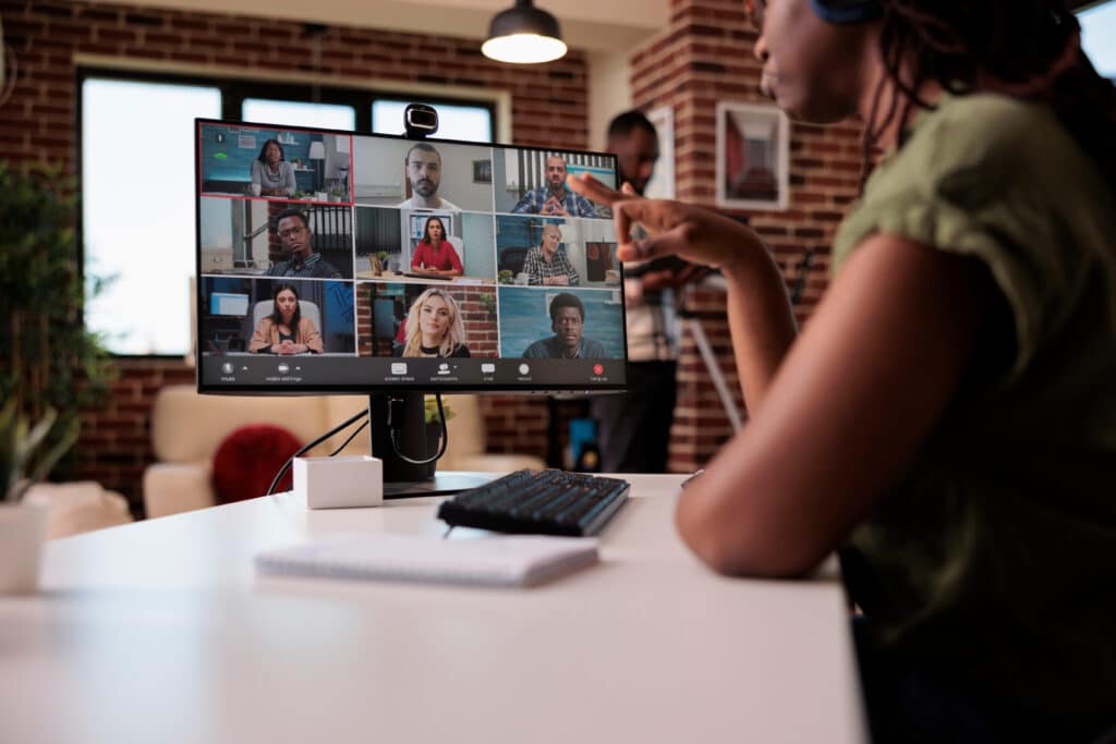 A lady looking at a computer monitor with a meeting on it representing work abroad
